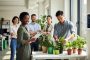 Diverse employees collaborating on sustainability in a bright modern office with potted plants and eco-friendly supplies, representing an employee green team.