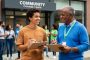 A mission-driven community change agent team prepares an outreach event in an urban community, with two leaders sharing a conversation and smiling in natural daylight.